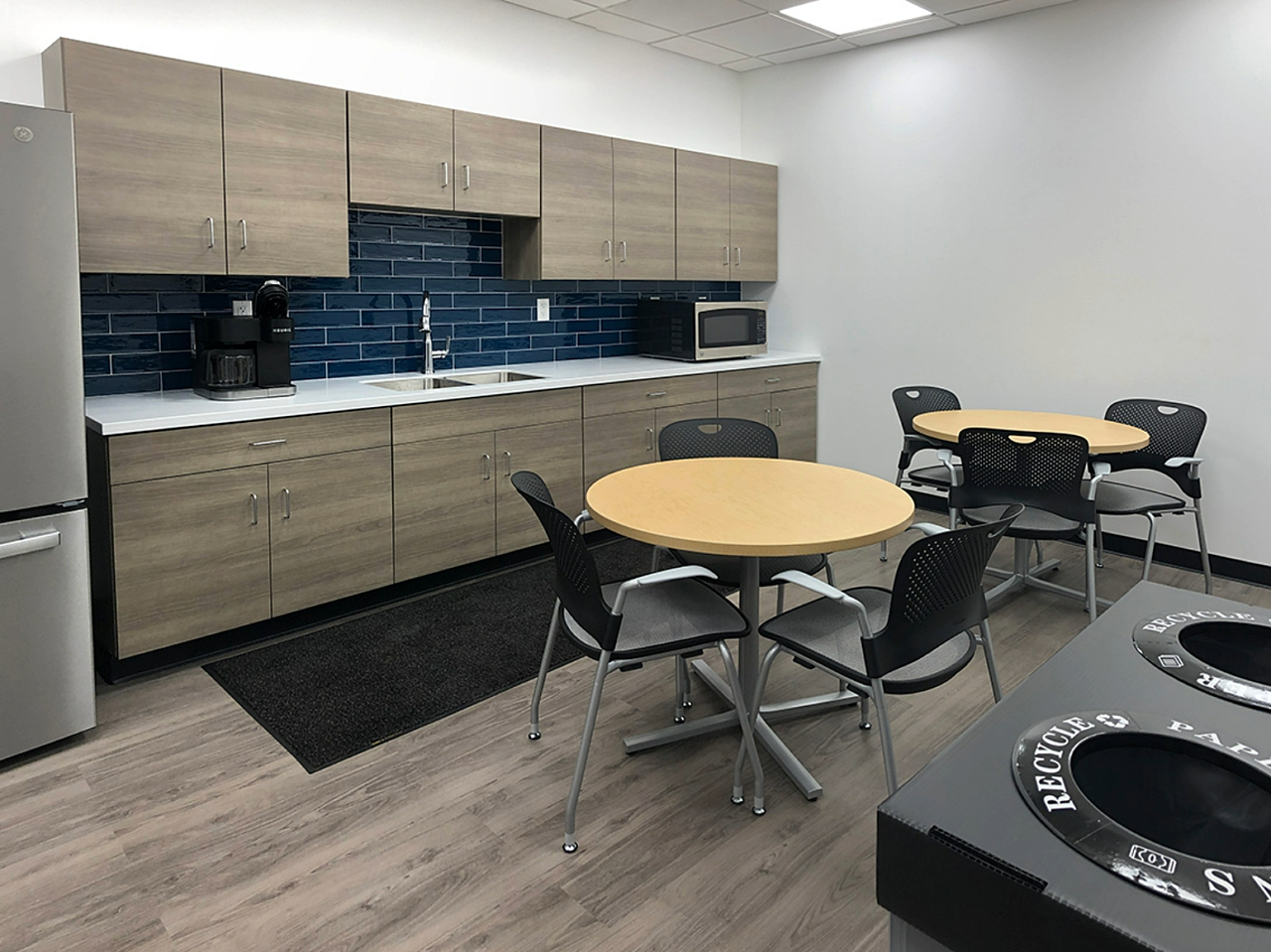 Breakroom kitchen with table & chairs, refrigerator and trash receptacles..