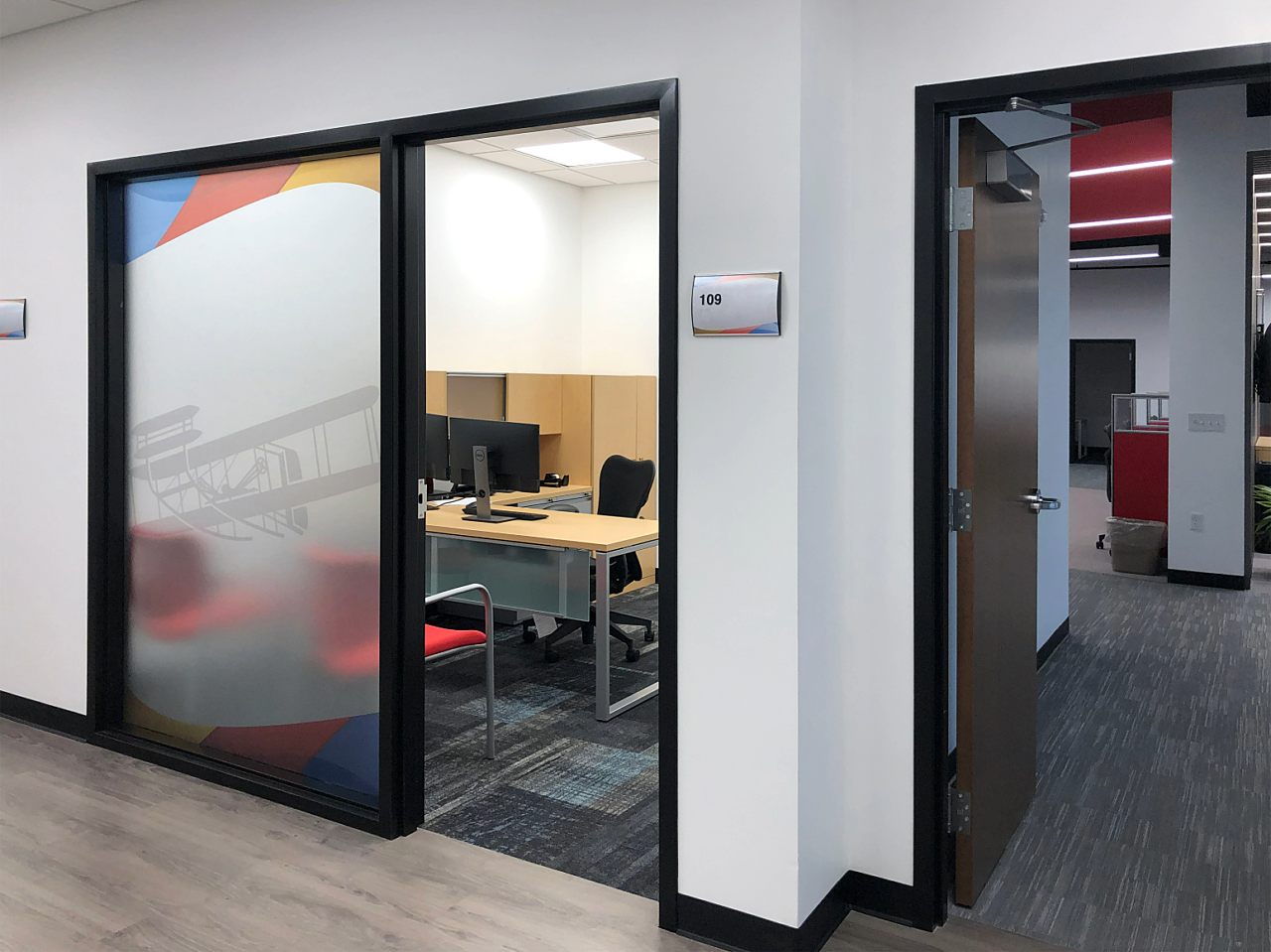 A spacious office with a large glass door, offering a clear view of the outside world.