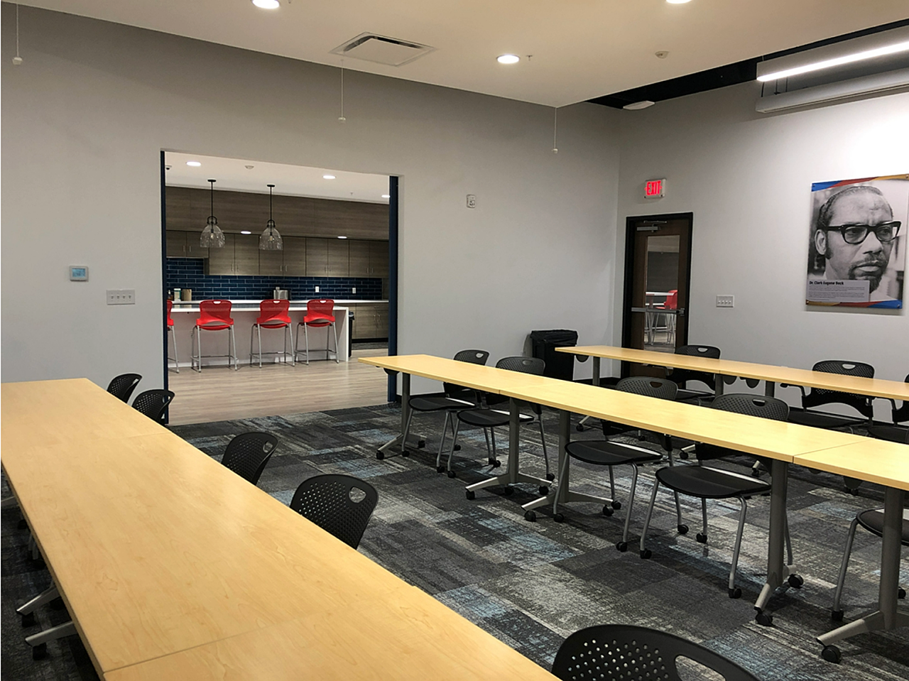 Presenter's view of the training room full of long tables and chairs. Cafe can be seen beyond the door in back of the room.