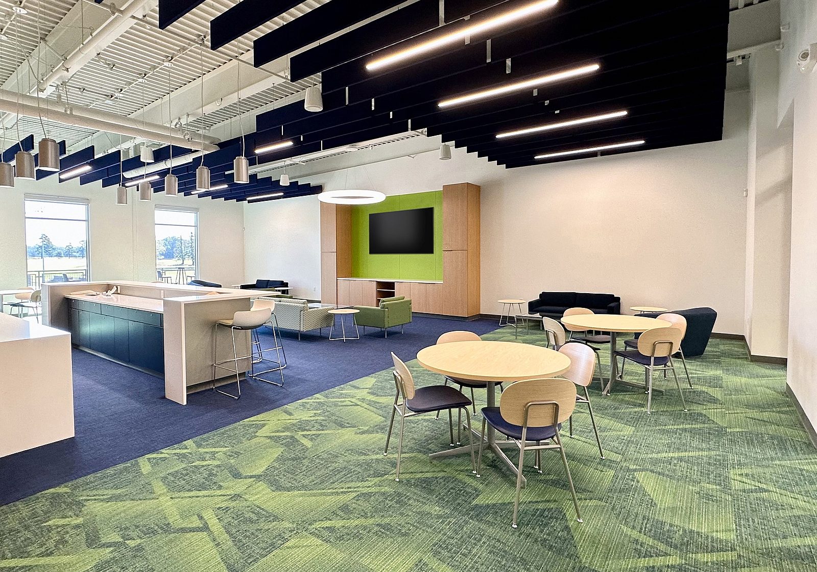 A cozy yet elegant spacious lounge with casual seating, tables with chairs, and a bar area. Well-lit with tall windows, it is ideal for socializing.