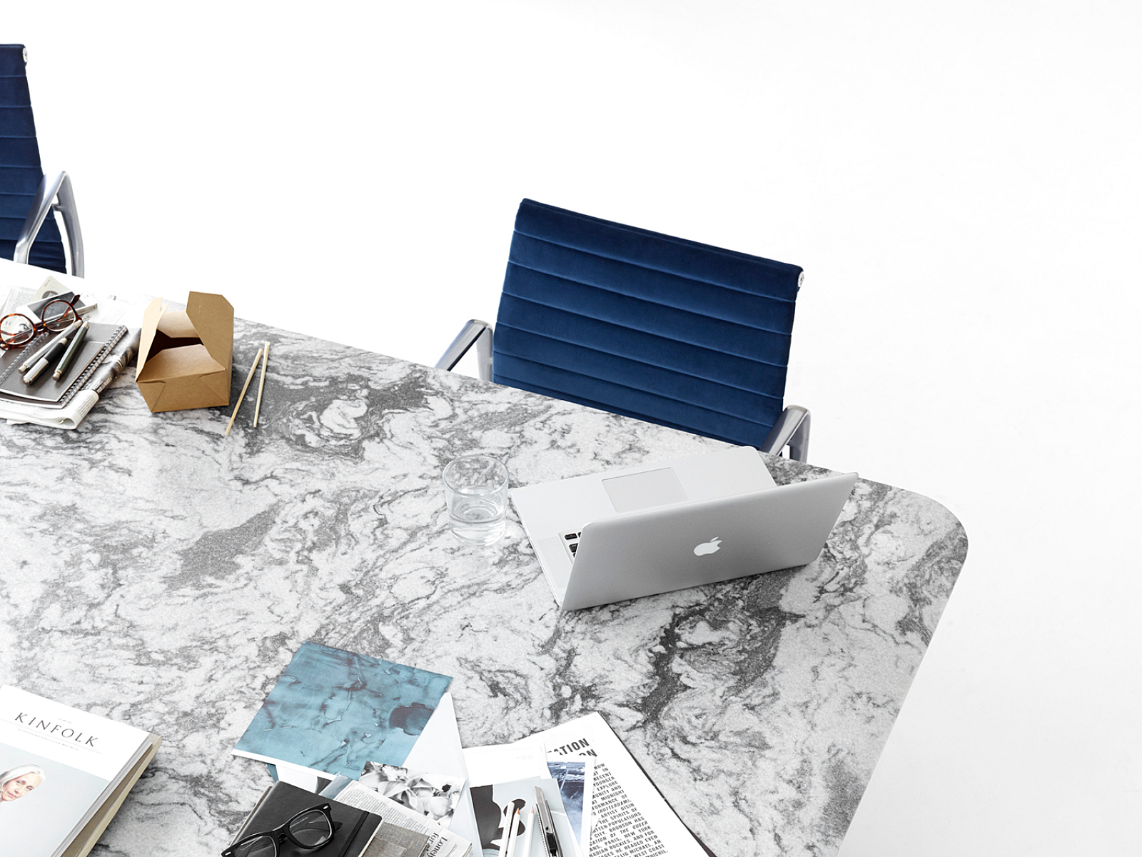Overhead view of Quartz conference table with computer, books, and personal accessories. Blue leather chairs.