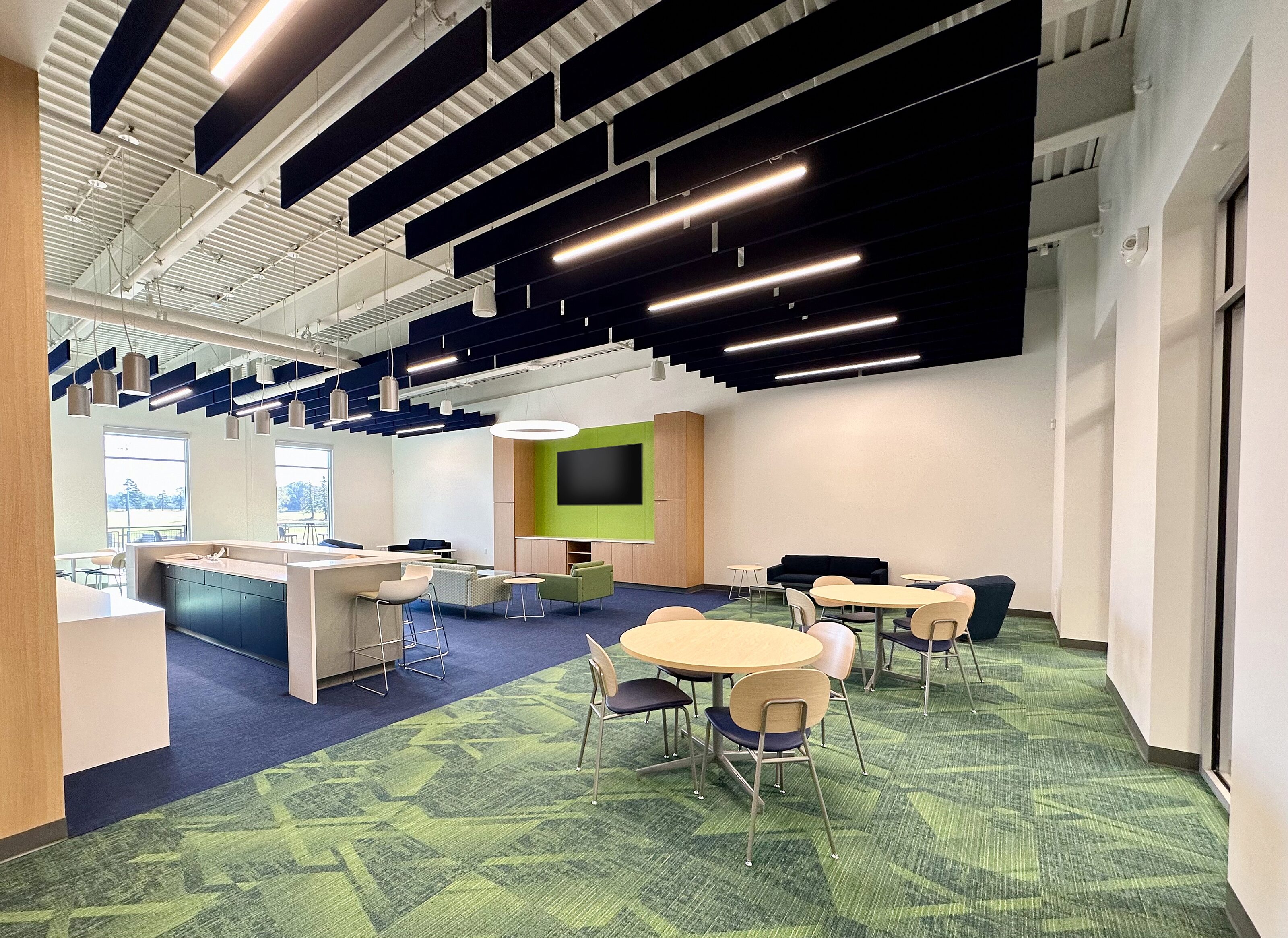 A modern tennis lounge featuring comfortable seating, a sleek interior design, and large windows allowing natural light to fill the space.