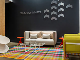 Clean, modern waiting area with colorful rug. Birch wall on left, dark wall in back & white tile wall on right. White sofa and lime green club chairs