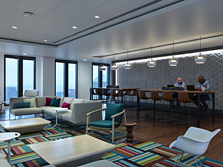 Collaborative gathering space with comtemporary lounge seating, plush rug, bar-height meeting table and richly textured wall.