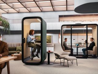 Person working in the foreground, person on a meeting in a single office phone booth, and two people meeting in a larger office pod in the background.