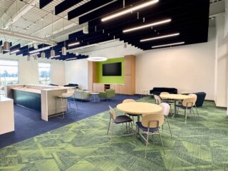 A cozy yet elegant spacious lounge with casual seating, tables with chairs, and a bar area. Well-lit with tall windows, it is ideal for socializing.