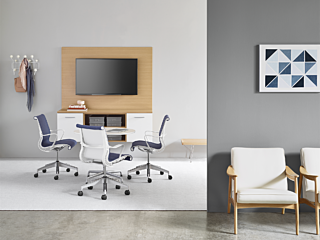 Calm waiting area with inviting meeting room in the background featuring a table, rolling leather chairs, and video screen on the wall.