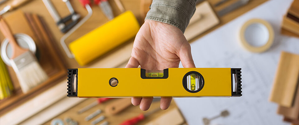 Flat-lay view of construction tools with hand holding a yellow bubble level