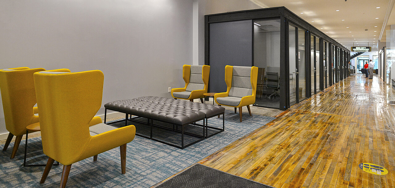 An inviting lounge area featuring stylish yellow and gray chairs and a table, designed to create a welcoming atmosphere for both guests and staff.