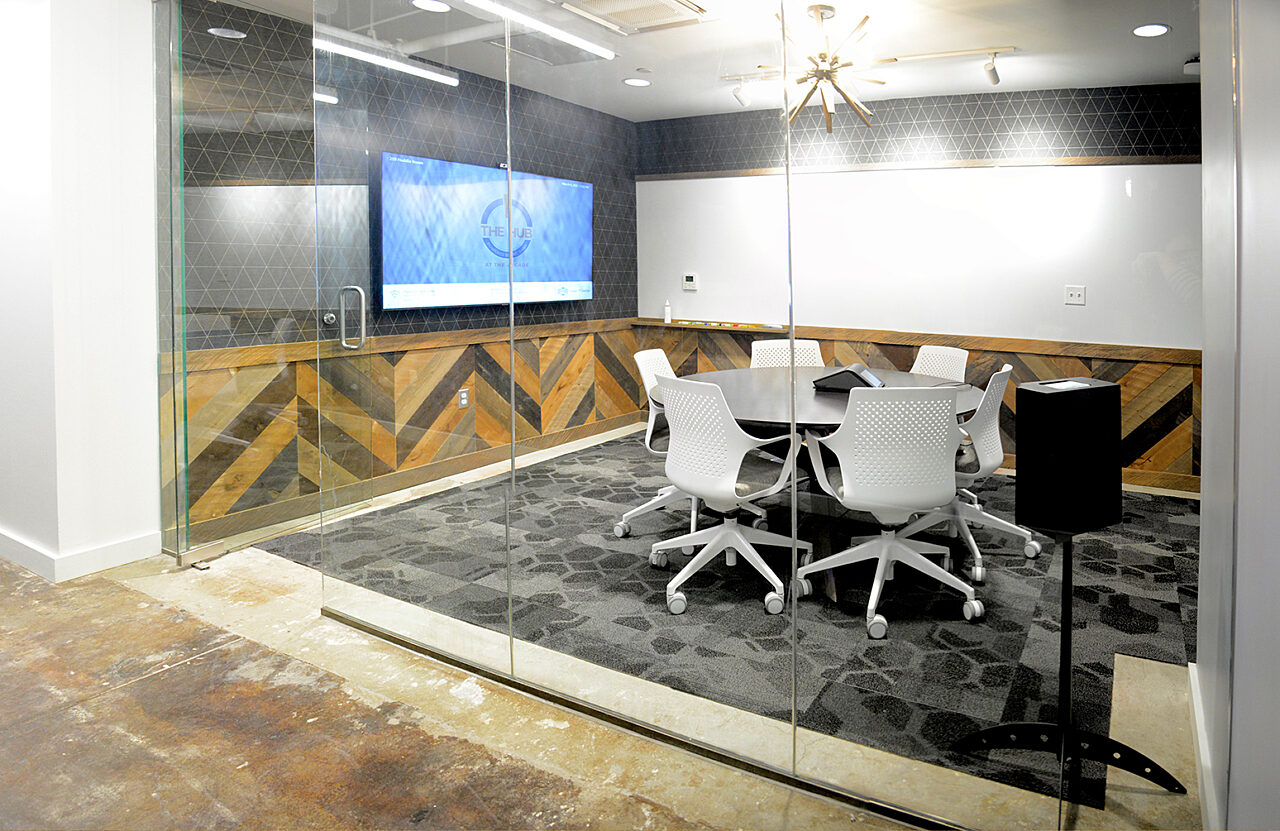 An organized conference room with a glass wall showcasing a large screen and multiple chairs set up for a meeting