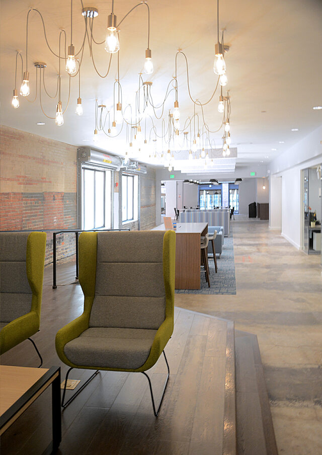 An inviting office lobby featuring stylish yellow and gray chairs and tables, designed to create a welcoming atmosphere for both guests and staff.
