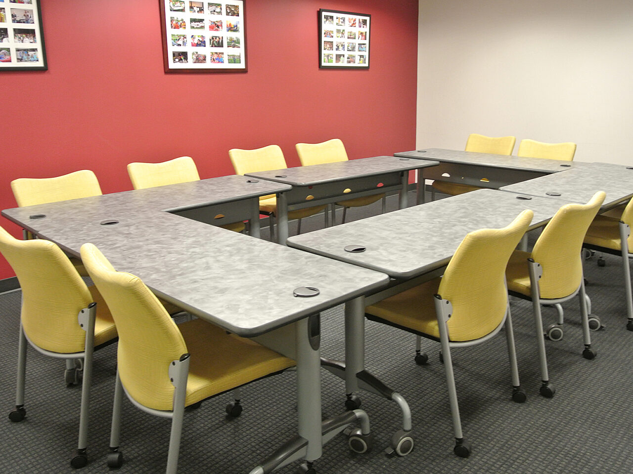 A conference room featuring yellow chairs arranged around a few tables, designed for meetings and collaborative discussions.