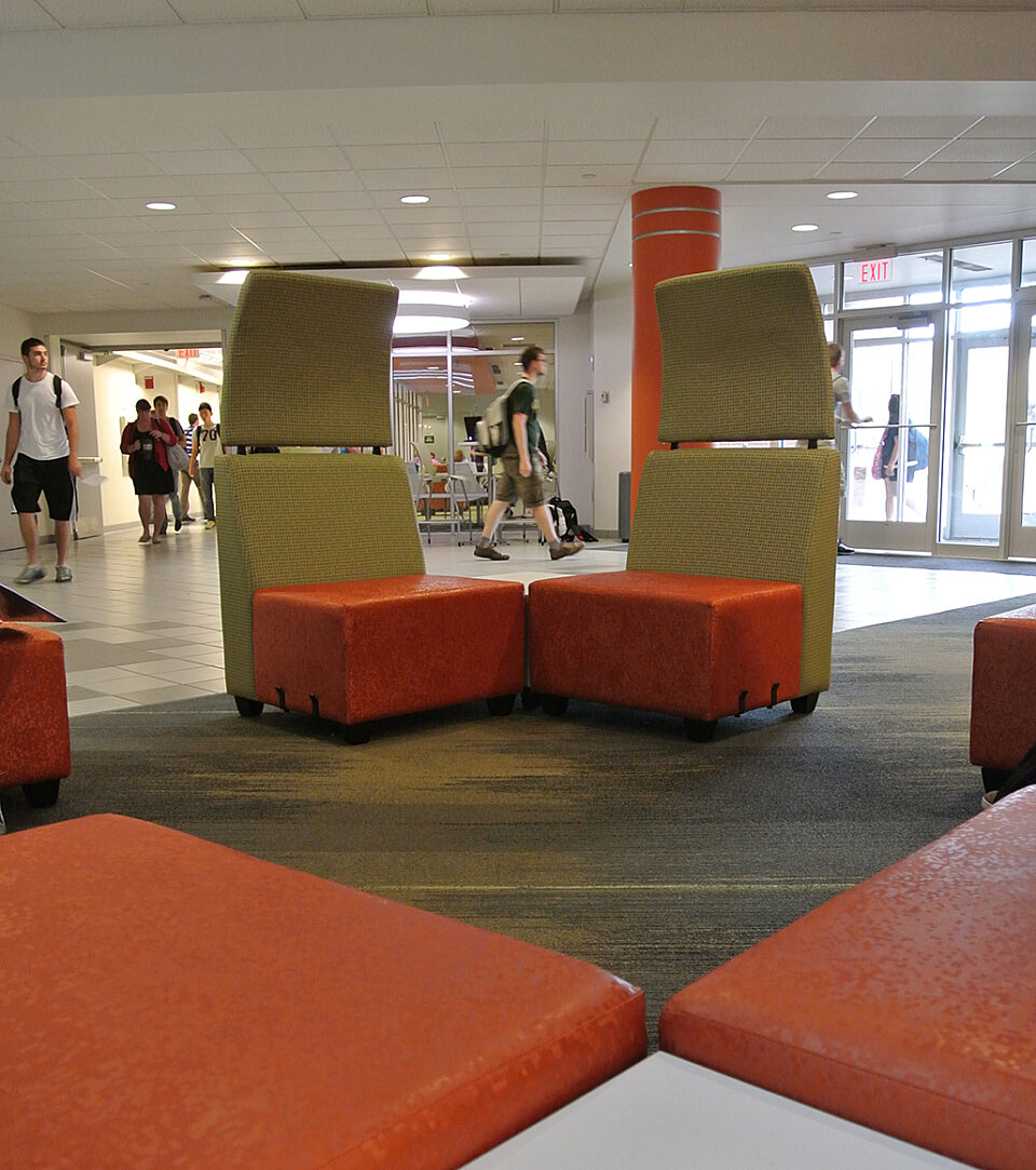 A large lobby with stylish orange chairs, designed for comfort and inviting social interaction.